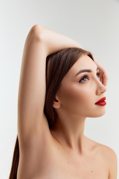 Foto ternura feminilidade jovem linda menina morena com maquiagem de lábios vermelhos posando sobre estúdio cinza