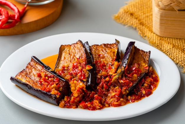 Terong Balado ou Berinjela com Sambal Balado Servindo em Prato Branco sobre Fundo Cinza