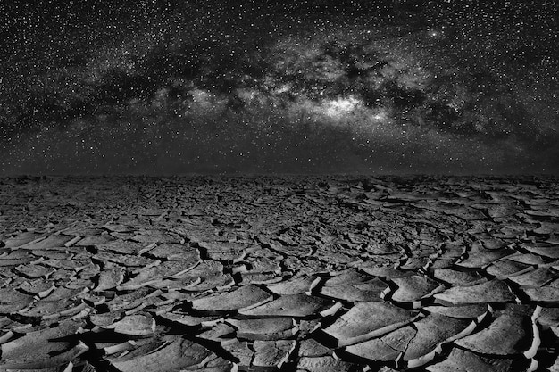 Terra seca e espaço rachados do universo da galáxia da via látea no céu noturno.