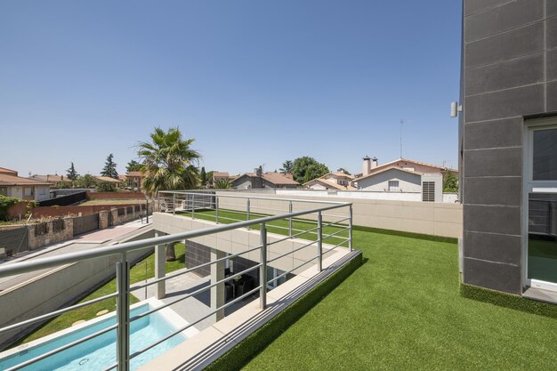 Terraço coberto com relva artificial com vista para uma piscina de verão