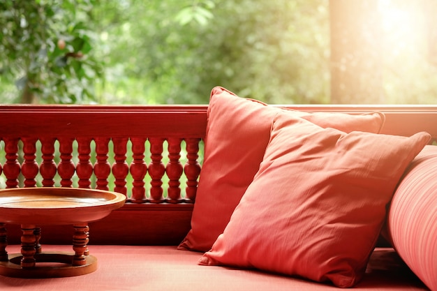 Terraço com um travesseiro e uma pequena mesa de madeira. Natural fresco verde
