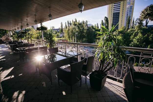 terraço do restaurante de verão com plantas verdes, mesas para visitantes, dia ensolarado de verão
