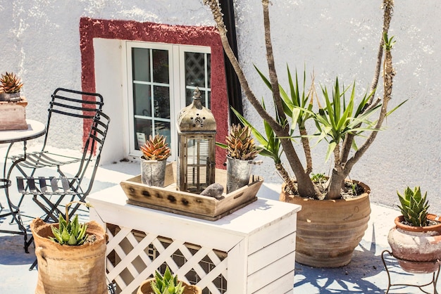 Terraço em estilo grego com vasos de flores decorativos e móveis de jardim em Santorini, Grécia