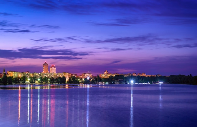 Terraplén de la ciudad europea moderna con iluminación nocturna y cielo colorido. Tarde en el río Dnieper en Obolon, Kiev