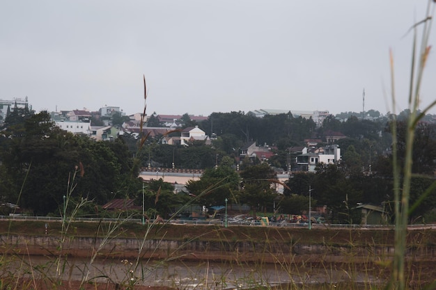 terras altas com colinas verdes e cidade perto da margem do rio Dak RTih com céu nublado em Gia Nghia Daknong