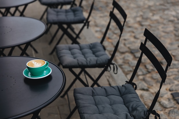 Terraza de la cafetería donde se sirve una taza de color turquesa de sabroso capuchino aromático