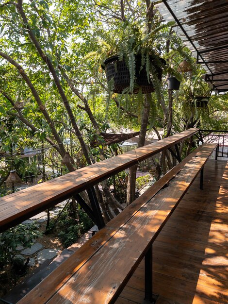 Foto la terraza de madera con el banco largo y la planta tropical para relajarse en el segundo piso en la vista frontal de la casa de campo con el espacio de copia