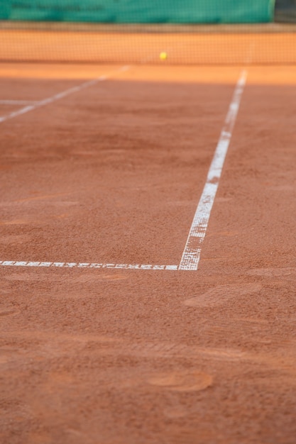 Terreno en cancha de tenis con líneas blancas a la luz del día.