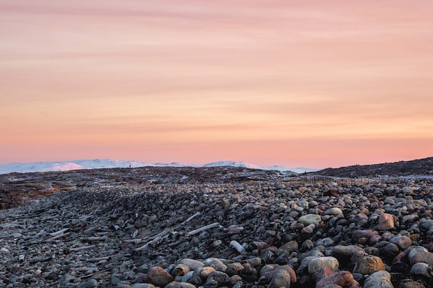 Terreno geológico complexo. paisagem polar do nascer do sol incrível com um cume de neve branca de montanhas atrás das montanhas rochosas e um penhasco. teriberka.