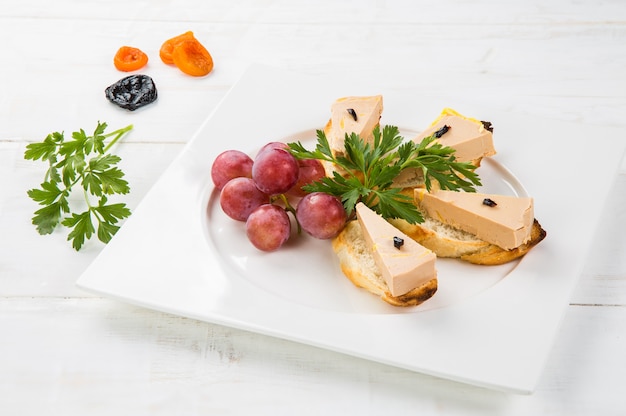 Terrina de foie gras delicioso com geléia de figo em uma mesa de madeira branca