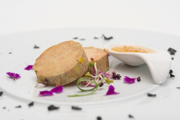 Terrine de fígado servido com molho doce, decorado com pétalas de flores, folhas verdes