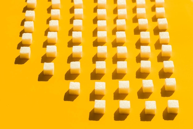 Terrones de azúcar blanco dispuestos en líneas diagonales sobre fondo amarillo