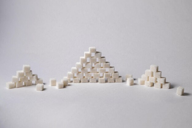 Foto terrones de azúcar en forma de pirámide sobre fondo blanco, imagen conceptual