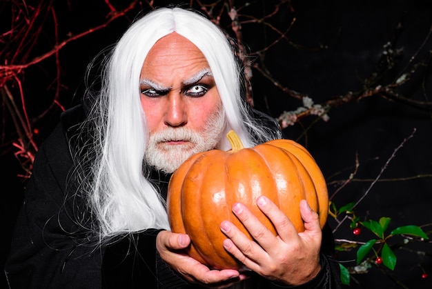 Terror de fantasia de Halloween. Homem assustador com abóbora. Fazendo Jack-o-lantern. Homem bonito com fantasia de férias.