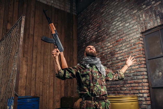 Foto terrorist mit kalaschnikow-gewehr hob die hände