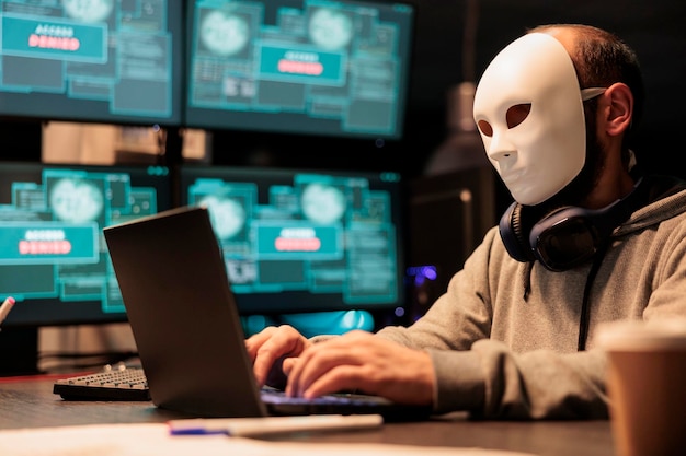 Foto terrorista cibernético usando servidores de banco de dados de hackers de máscara, hacker com capuz invadindo o sistema do computador e ativando vírus para criar malware. misterioso impostor roubando big data.
