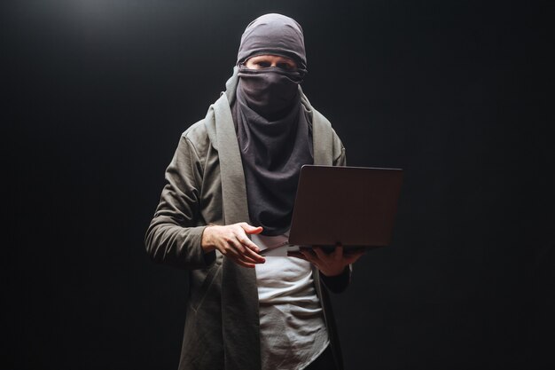 Terrorista com laptop em fundo preto