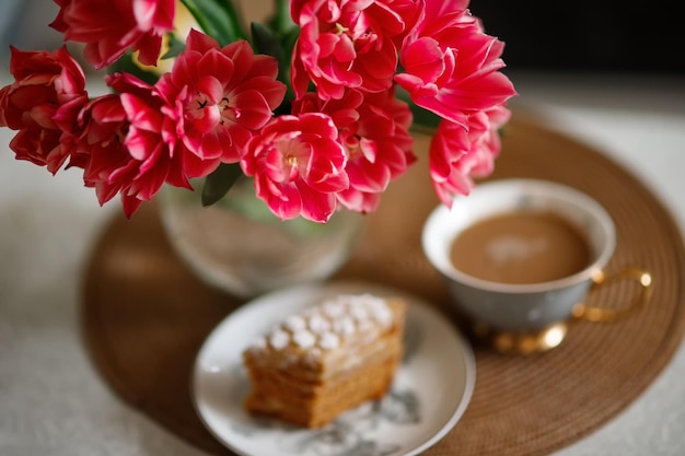 Terry rote Tulpen und undeutliche Tasse Kaffee und Kuchen