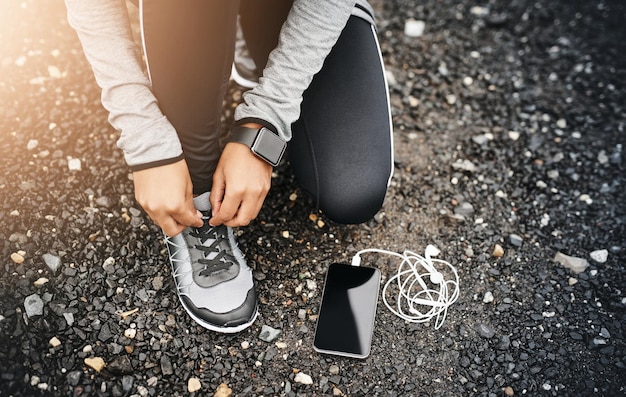 Átese los cordones y muévase Primer plano de una mujer deportiva atándose los cordones mientras hace ejercicio al aire libre