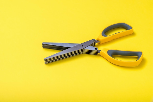 Tesoura com alças amarelas em um fundo amarelo