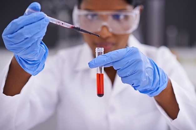 Testando amostras de sangue uma vista frontal de um jovem cientista soltando uma substância em um tubo de ensaio
