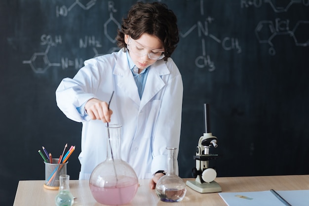 Testando novos equipamentos. A criatividade talentosa envolvia criança em pé no laboratório, aproveitando a aula de química enquanto demonstrava o experimento