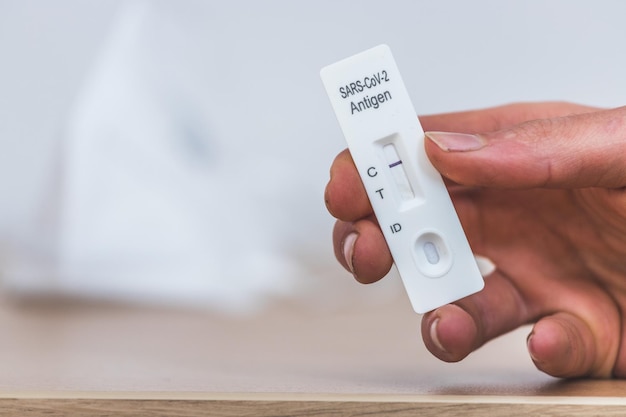 Teste de corona expresso em casa Fechamento dos dedos segurando uma máscara de teste de antígeno cobiçoso negativo ffp2 em segundo plano