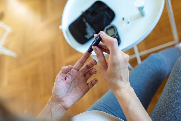 Teste de glicose no sangue para diabetes em mulher grávida com glicosímetro. Uma gota vermelha de sangue no dedo pronto para medir o nível de açúcar. Fechar o dedo masculino com gota de sangue e tira de teste