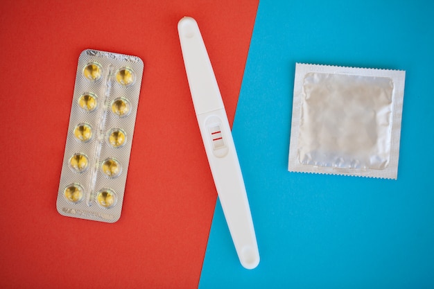 Teste de gravidez. O resultado é positivo com duas tiras e preservativo com contraceptivo colorido, pílula anticoncepcional, sexo seguro, conceito de assistência médica