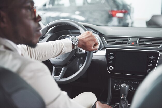 Teste de jovem empresário preto conduzir carro novo. rico homem afro-americano