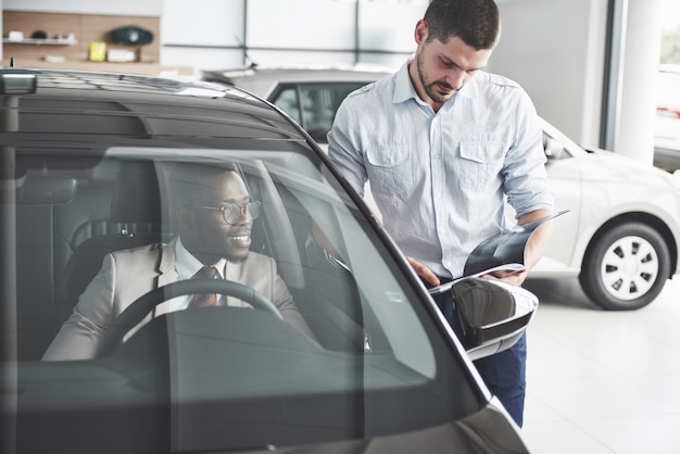 Teste de jovem empresário preto conduzir carro novo. Rico homem afro-americano