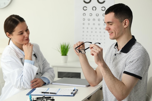 Teste de visão Jovem a tentar óculos no consultório de oftalmologista