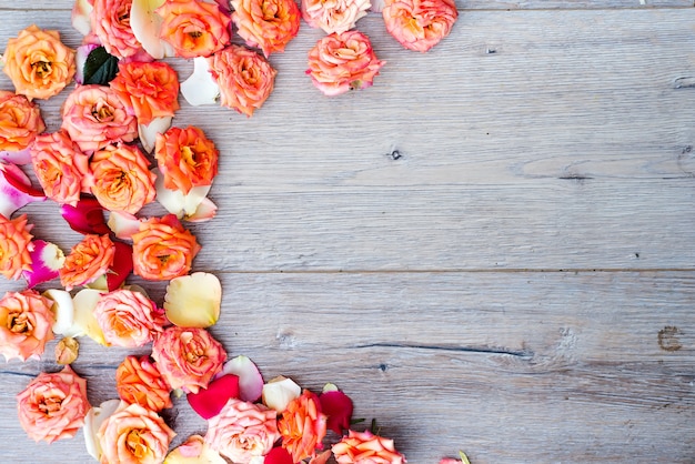 Teste padrão floral, moldura feita de rosas sobre fundo de madeira. Flat leigo, vista superior.