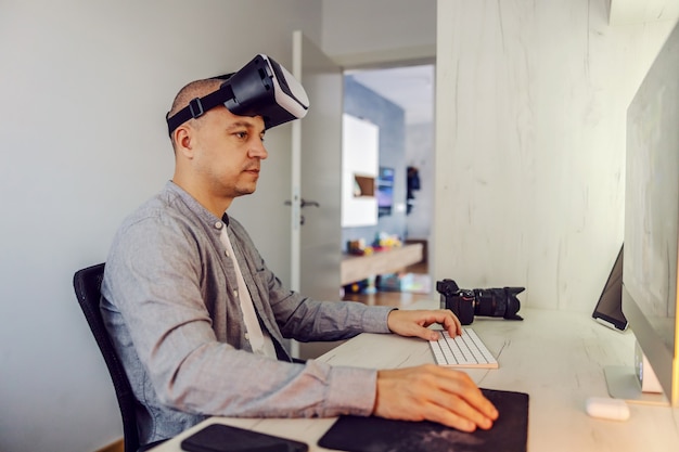 Testen Sie 3D Virtual Reality bequem von zu Hause aus. Ein erwachsener Mann mit einer Virtual-Reality-Brille auf dem Kopf testet 3D-Simulatoren