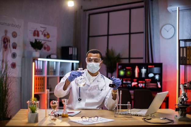 Testexperiment eines männlichen Wissenschaftlers in einem Wissenschaftslabor, in dem er ein wissenschaftliches Reagenzglas hält