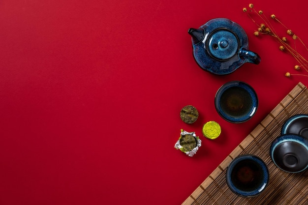 Tetera azul taza de té y hojas de té sobre fondo rojo El té de hierbas caliente está en la tetera sobre la mesa Espacio de copia