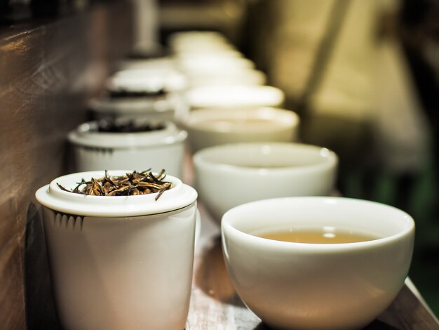 Tetera blanca y tazas con las hojas de té negro