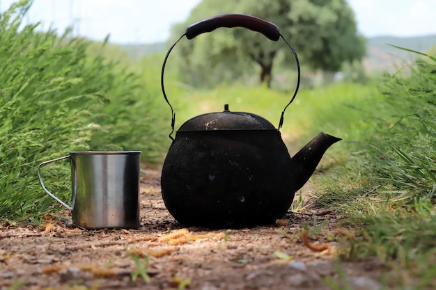 Tetera de camping negra y taza de metal.