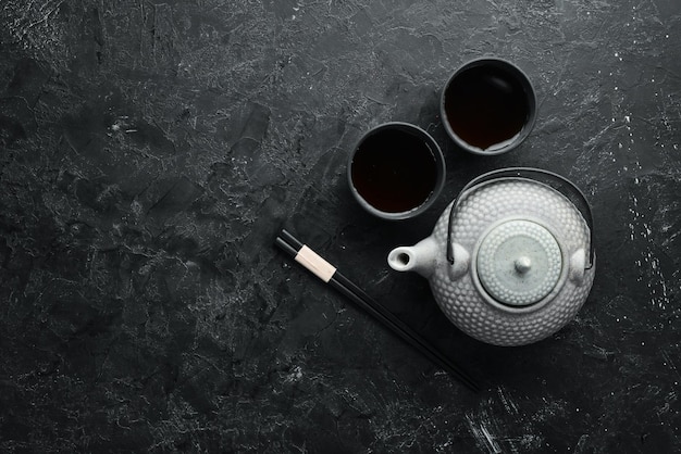 Tetera y dos tazas de té sobre un fondo de piedra negra Vista superior espacio libre para el texto