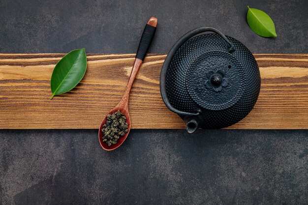 Tetera de hierro fundido negro con té de hierbas sobre piedra oscura.