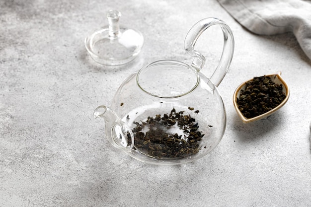 Tetera con hojas de té verde sobre un fondo gris en una mesa con una servilleta. Sin agua. tetera vacia