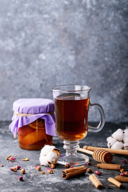 Una tetera de metal negro y una taza de té en un vaso de vidrio