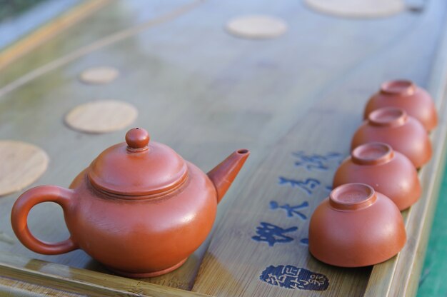 Tetera para preparar té y un tazón en una bandeja de madera