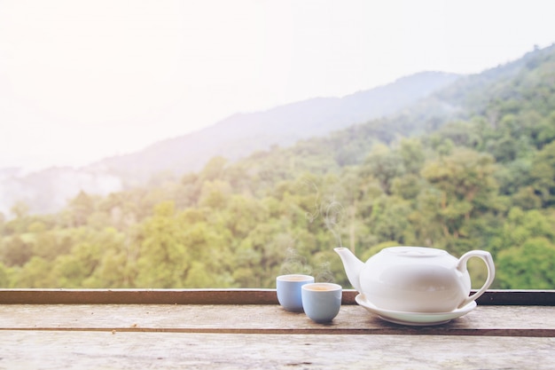 Tetera y taza de té caliente o caliente en la mesa de madera