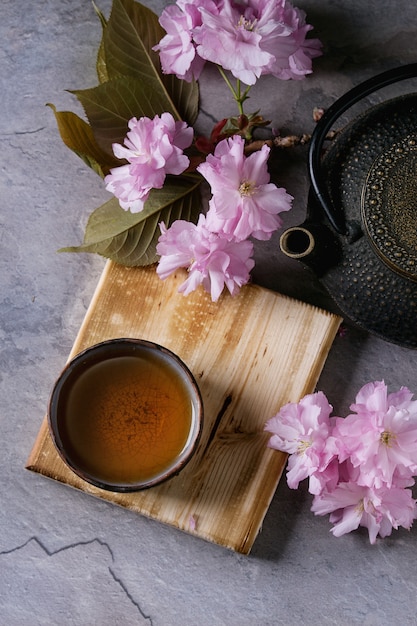 Tetera y taza de té con rama de flor