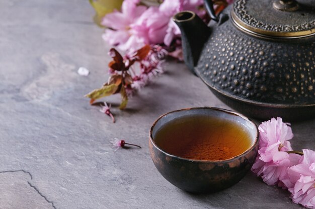 Tetera y taza de té con rama flor.