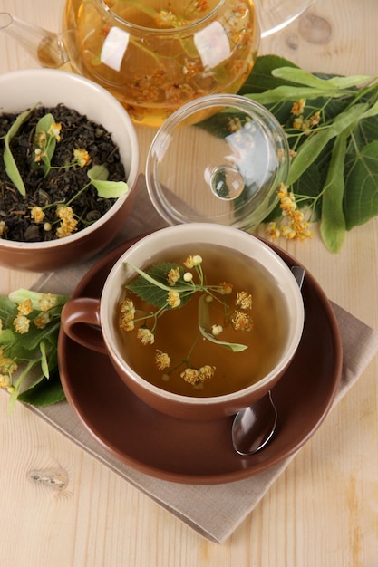 Tetera y taza de té con tilo sobre mesa de madera