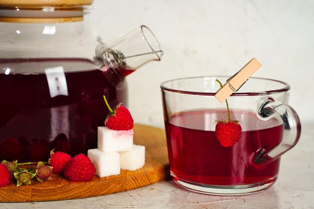 Tetera y taza transparentes con té dulce rojo con frambuesas Bayas de desintoxicación bebida saludable casera antioxidante Espacio de copia Foto de alta calidad