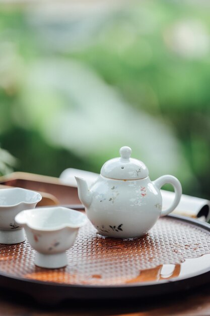 Una tetera y tazas sobre una mesa de fondo verde