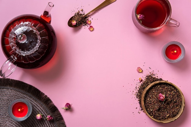 Tetera de vidrio taza de té y hojas de té sobre fondo rosa El té de hierbas caliente está en la tetera de vidrio sobre la mesa Espacio de copia